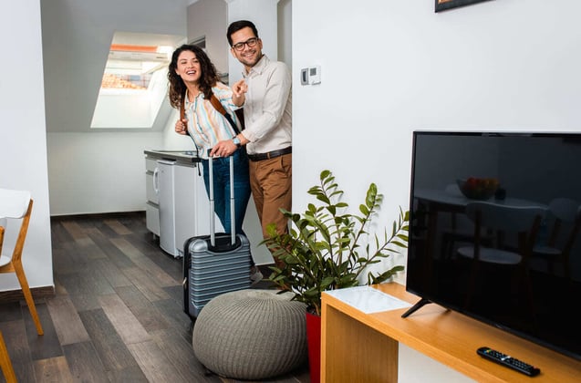 A couple entering a short-term rental property with suitcases