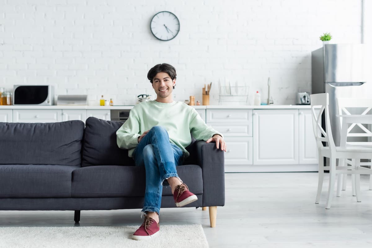 A man sititng on a couch in a home smiling