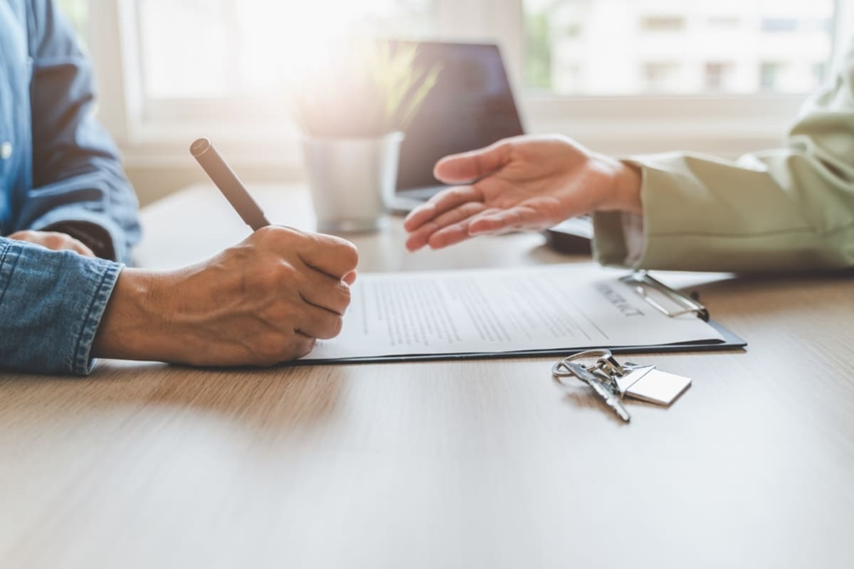 A real estate agent discussing a contract a buyer is signing, rental compliance concept