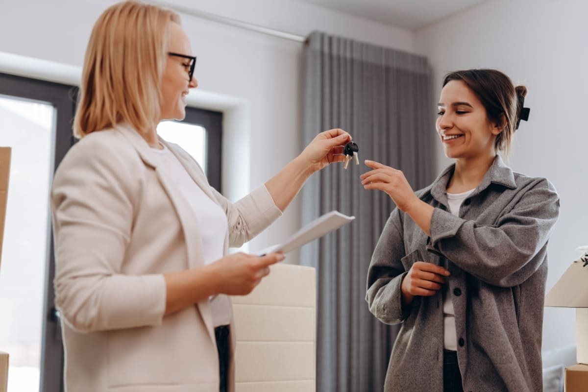 A real estate agent giving keys to a young woman, tenant rights concept