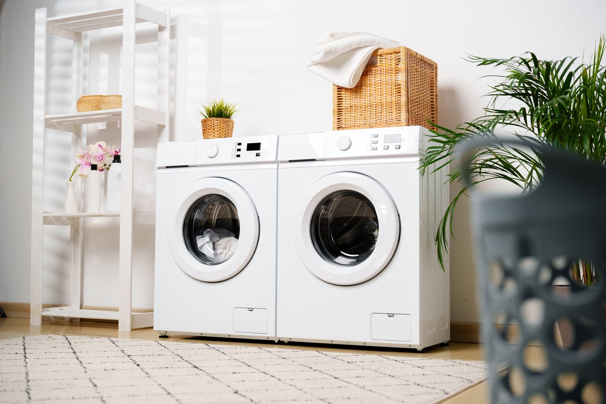 A washer and dryer with a basket stacked on top of it.