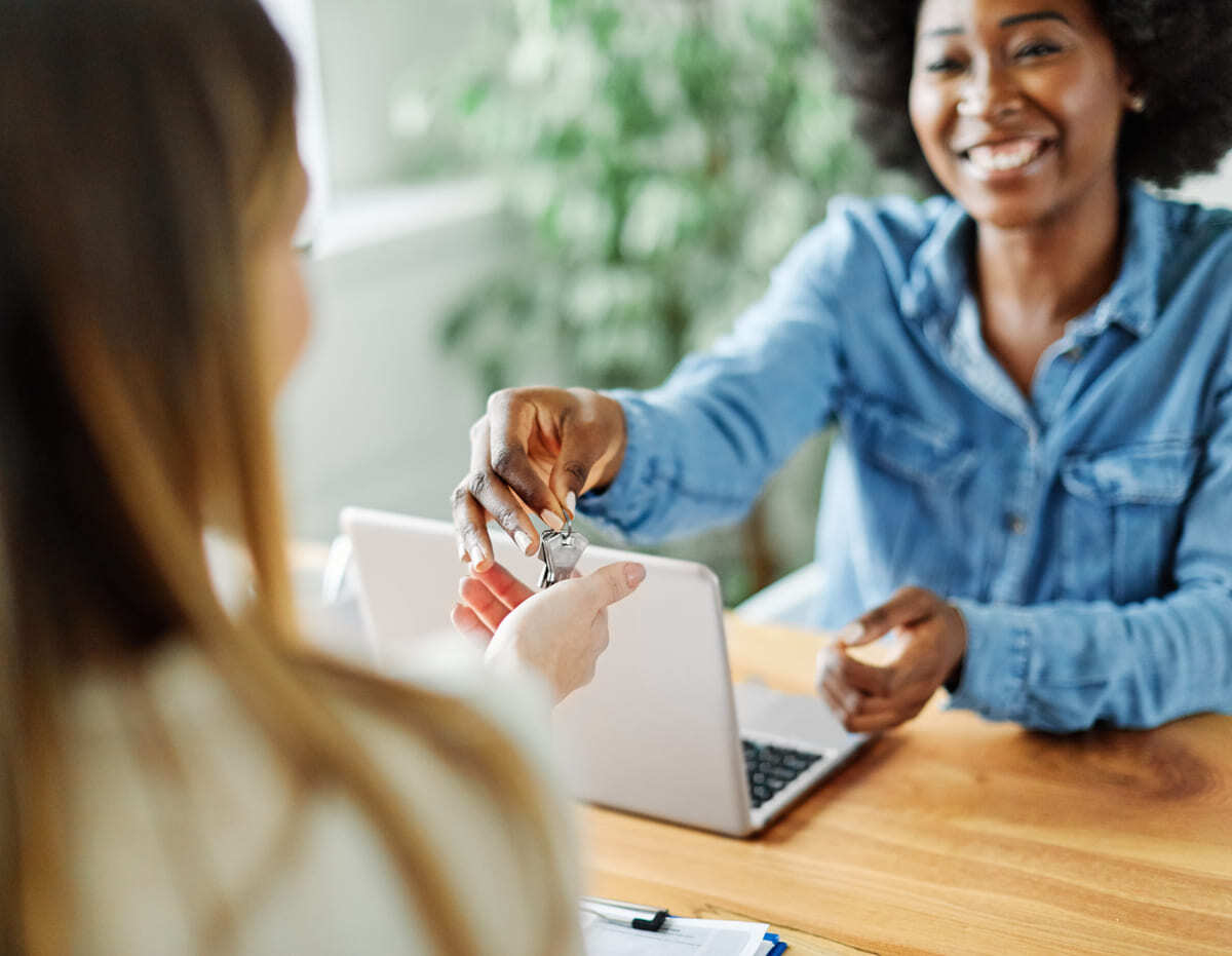 A woman handing another woman keys