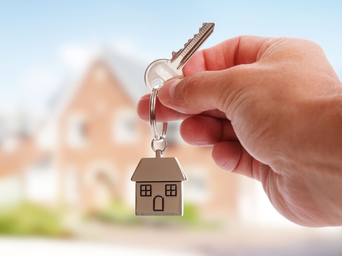 Carrying house keys on house-shaped key chain in front of a new house