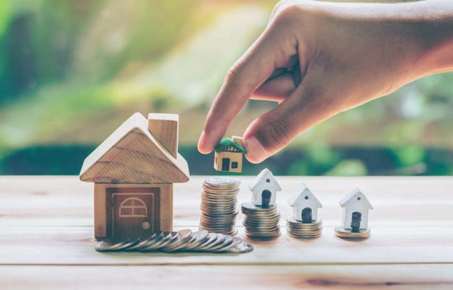 Tiny homes next to a stack of coins, property management concept. 