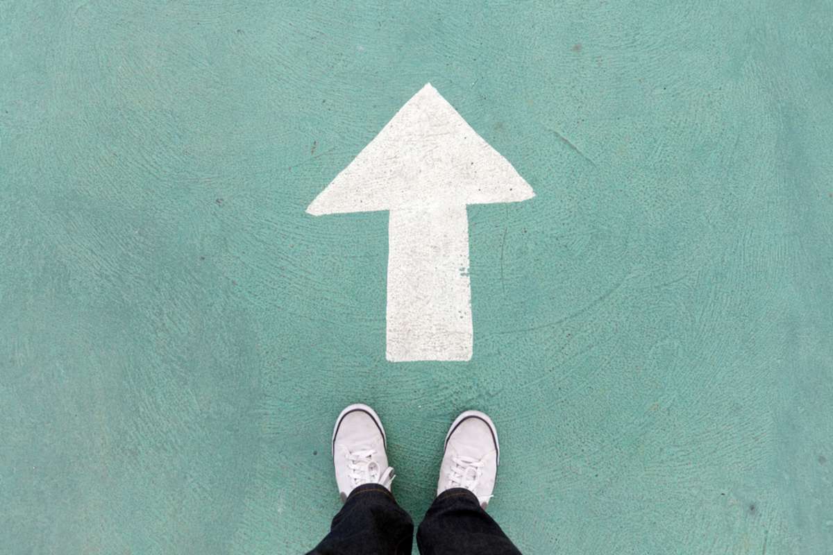 shoes standing on the concrete floor and white direction sign to go ahead