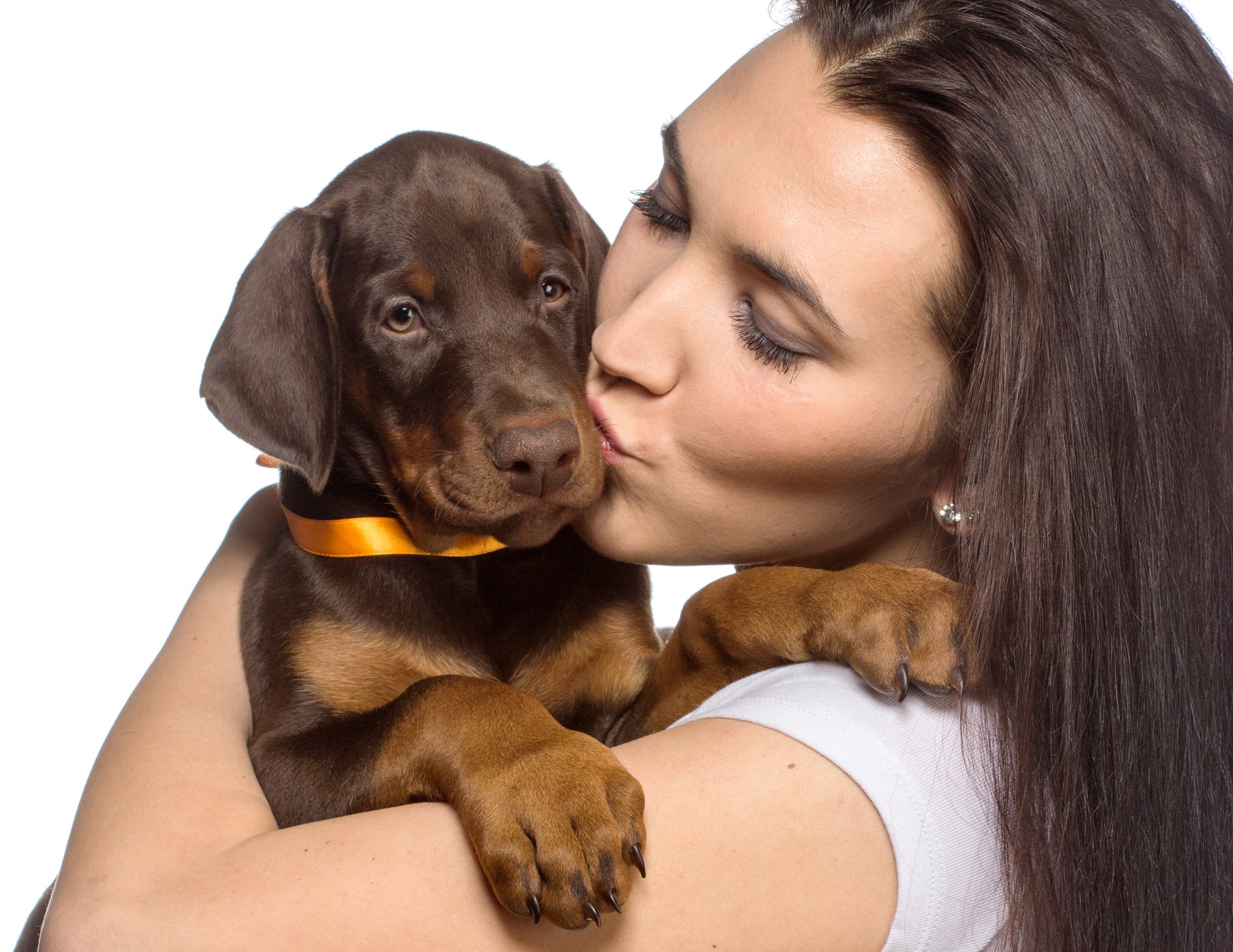Brunette girl kissing her puppy isolated on white background
