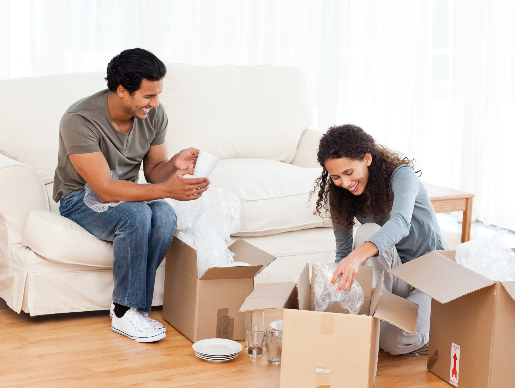 Happy couple packing glasses together in the living-room