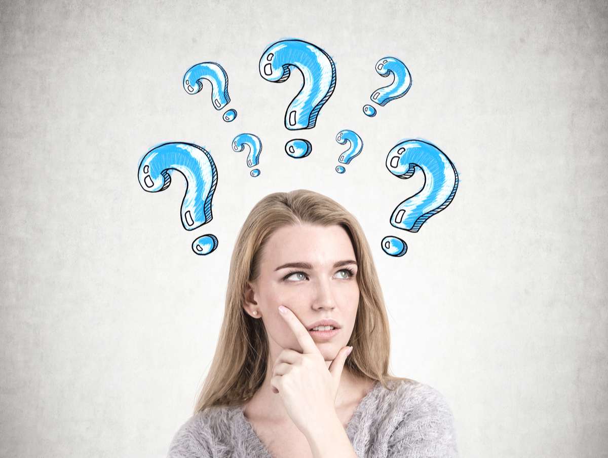 Head and shoulders portrait of a gorgeous young woman blue question marks on a wall (R) (S)