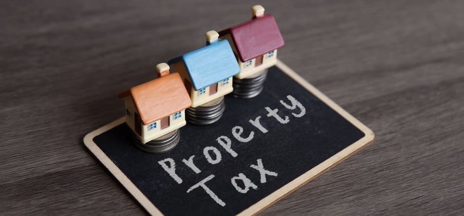Property taxes written on a black board next to small houses