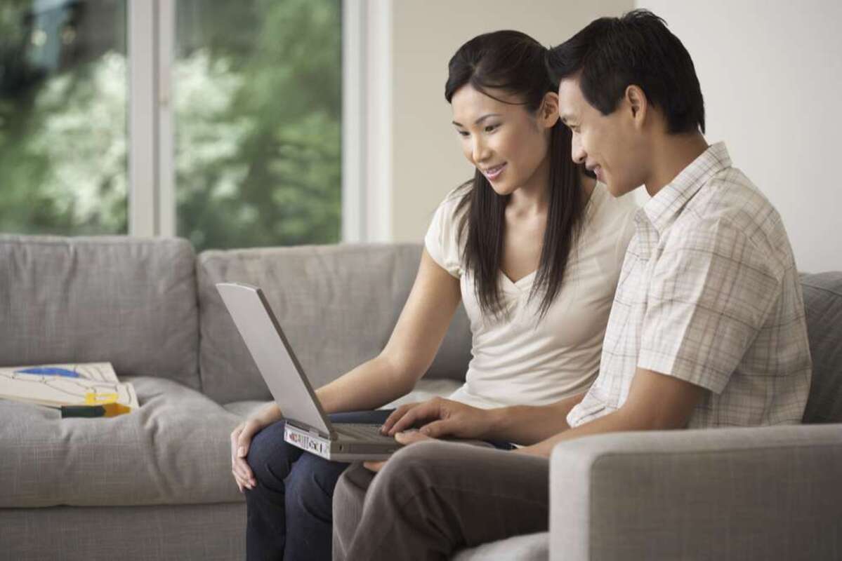 Side view of a young couple sitting on sofa and using a laptop (S) (R)