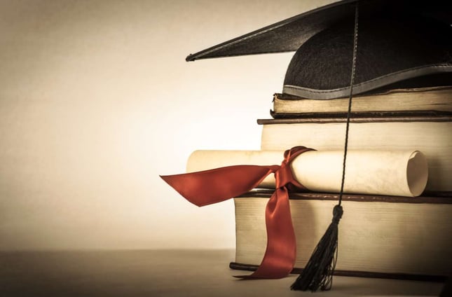 A carton of mortar boards and a graduation scroll