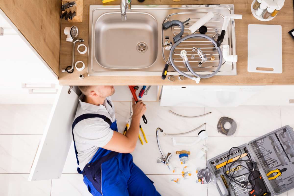 A professional plumber working under a sink, Seattle property management concept