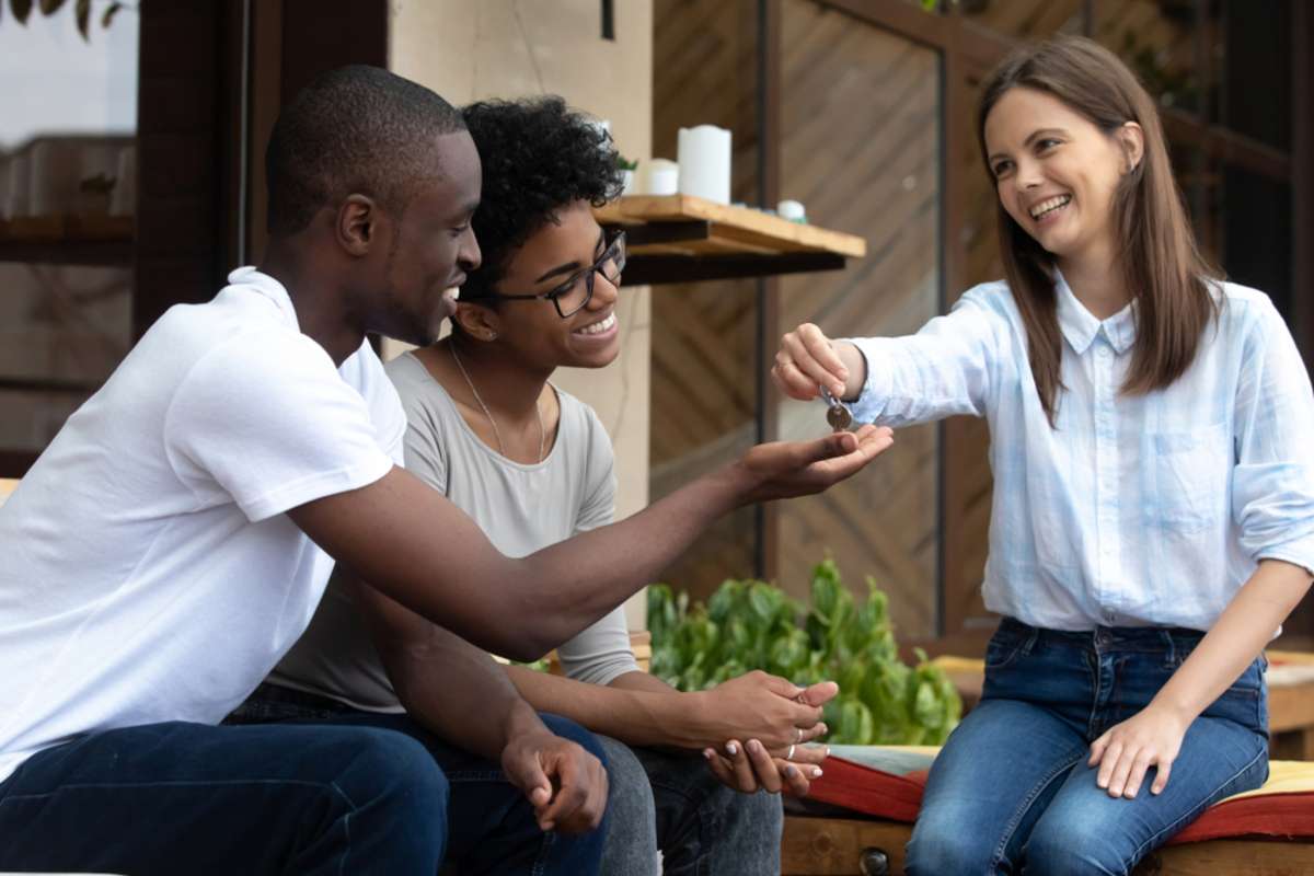 Happy black couple getting keys to their new apartment from young woman real estate agent