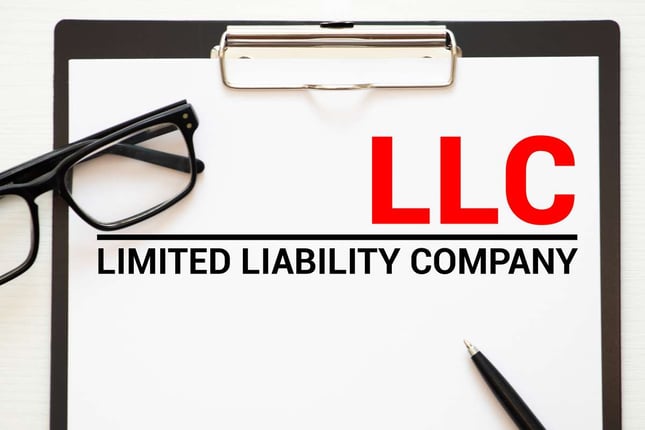 "LLC Limited Liability Company" on a clipboard, rental property LLC concept. 