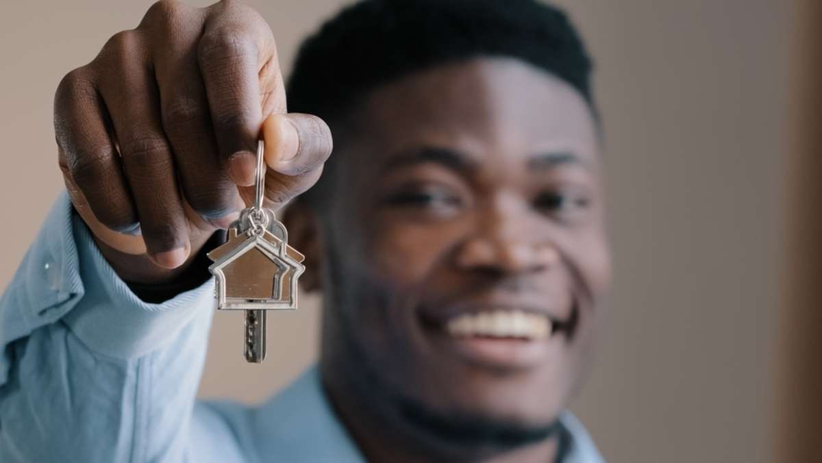 Overjoyed young african american male happy homeowner realtor win apartment in lottery excited young man own flat buyer real estate agent showing bunch of keys