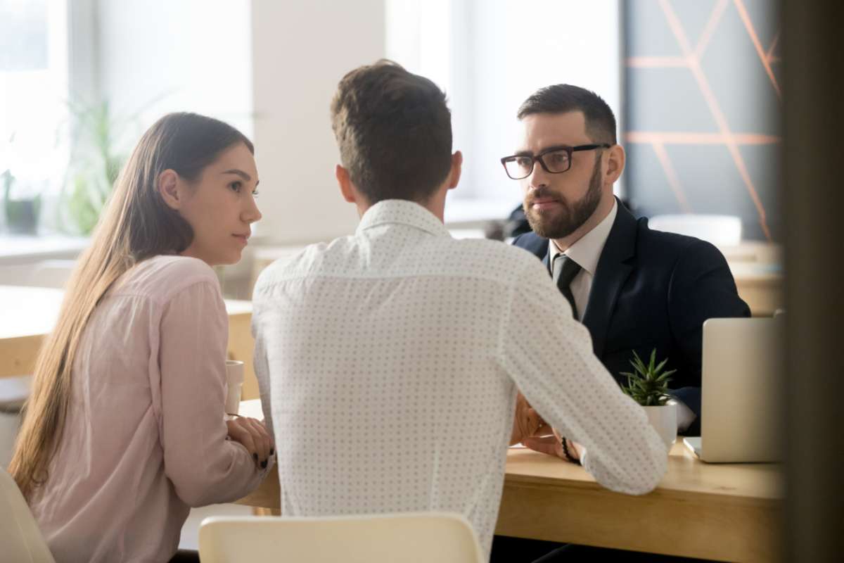 Serious broker or realtor listening to millennial couple arguments or ideas during office meeting