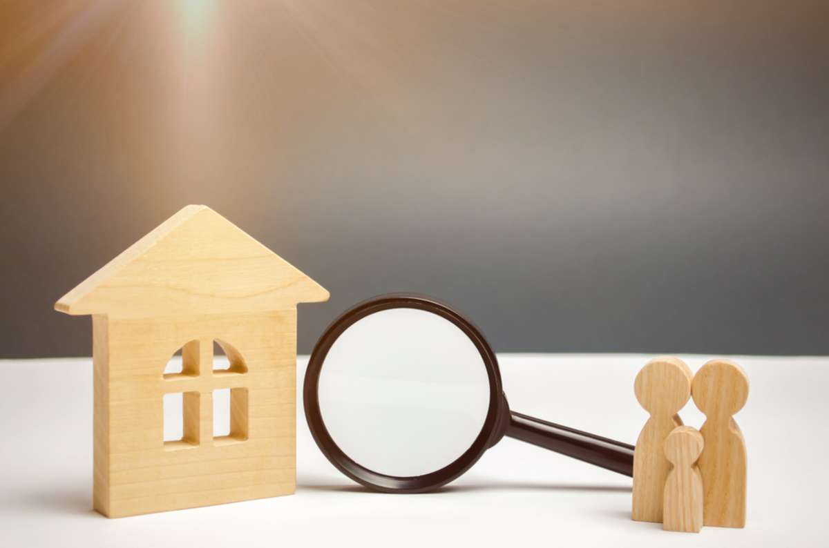 Wooden house and magnifying glass with family. Property valuation