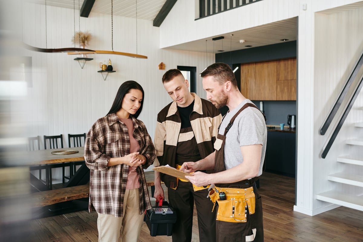 Woman Discussing Plans with Two Repairmen Indoors