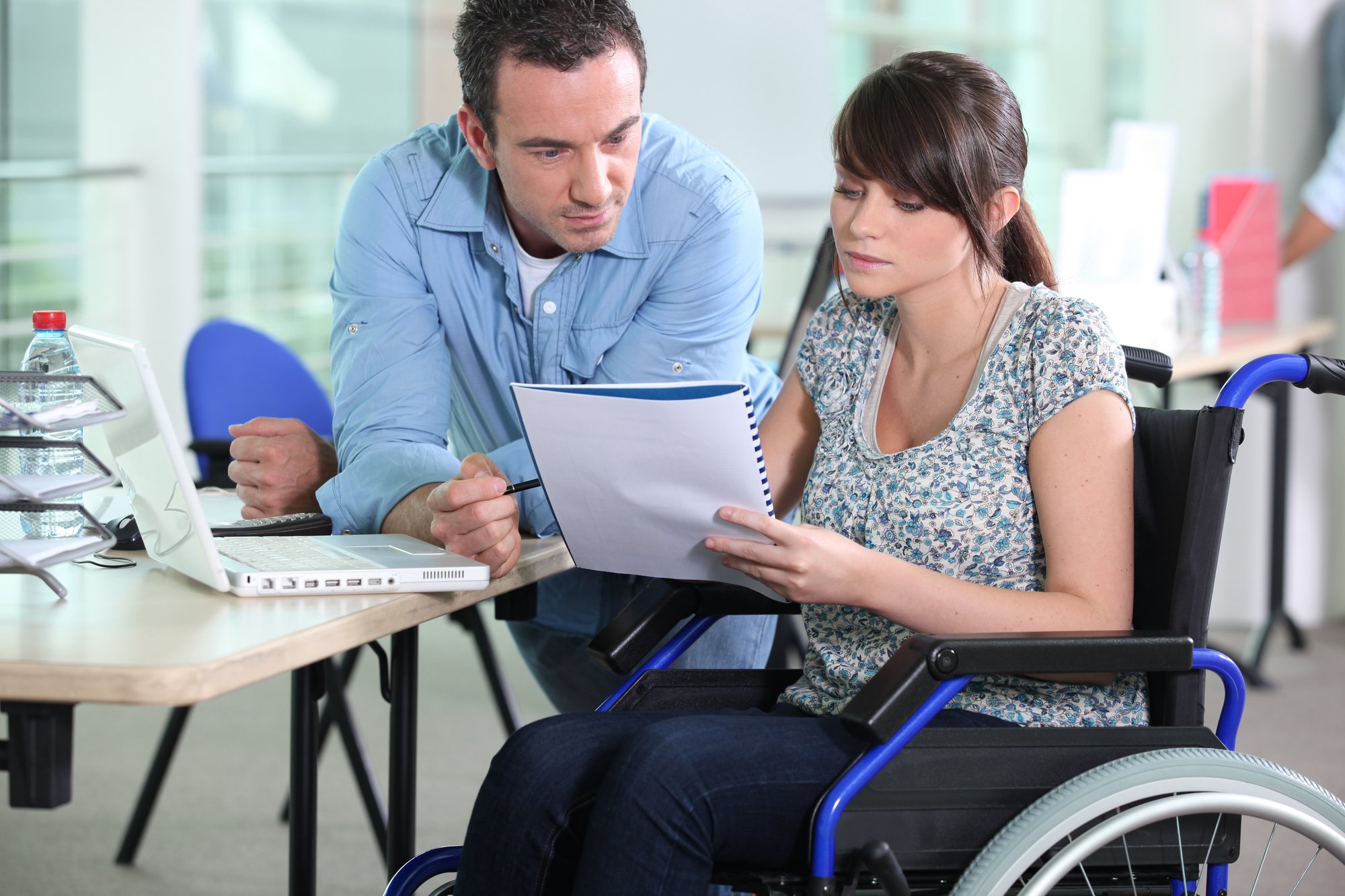 Young woman in wheelchair working with a male colleague