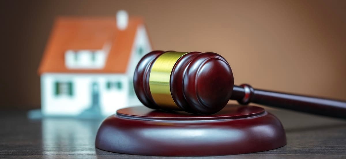 A judge gavel in front of a model home