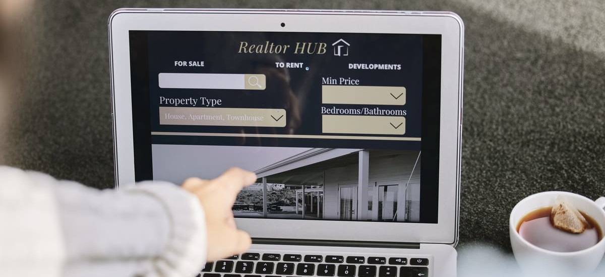 A woman looking at an online property listing on a laptop