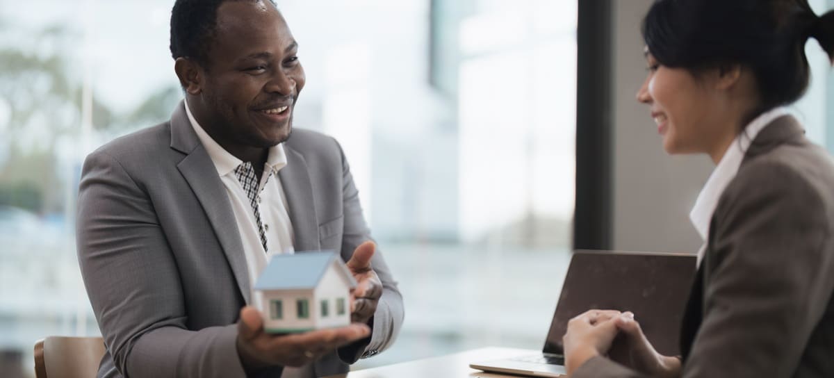 A man holding a model home and talking to a woman