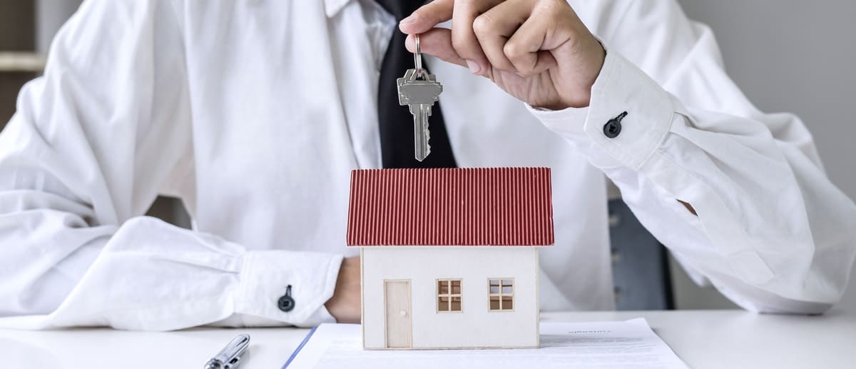 A man holding keys over a small home