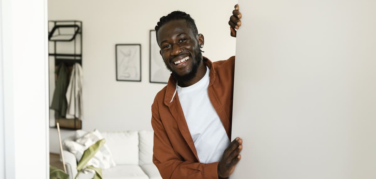 A man holding the door open to his home
