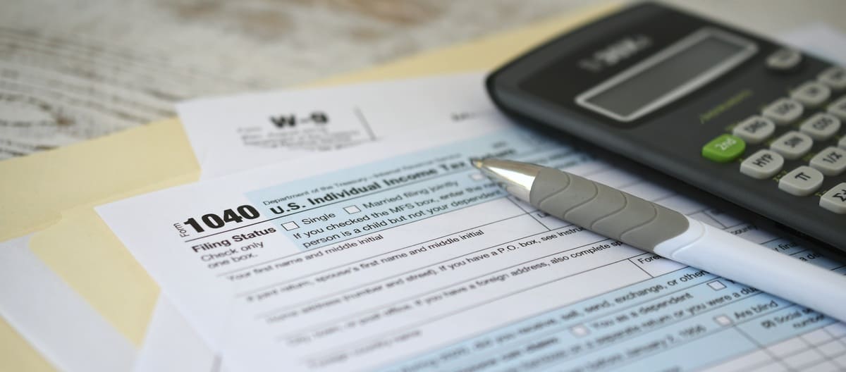 A pen and a calculator on top of tax documents