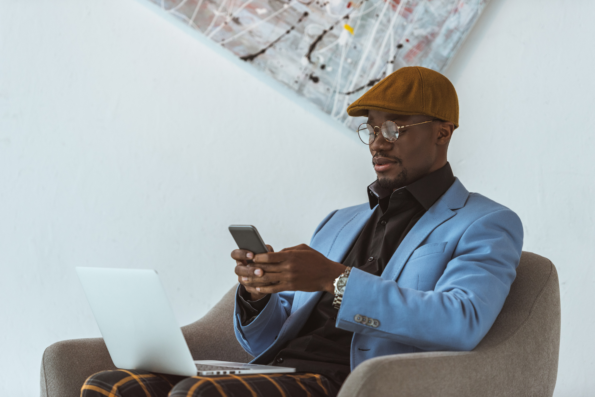 Man working with laptop while holding mobile phone