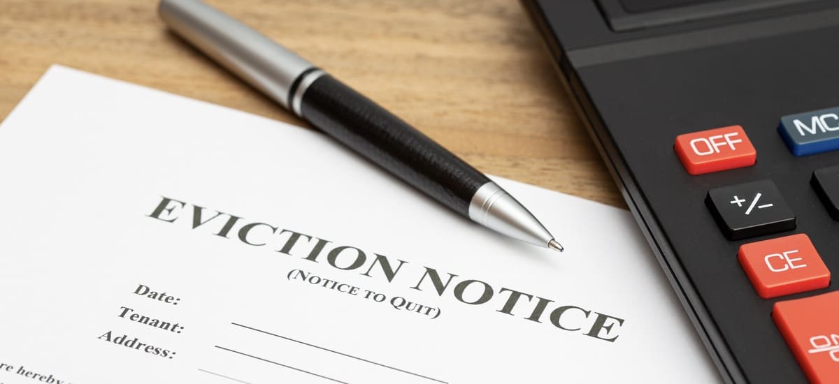 An eviction notice on a table next to a pen and a calculator