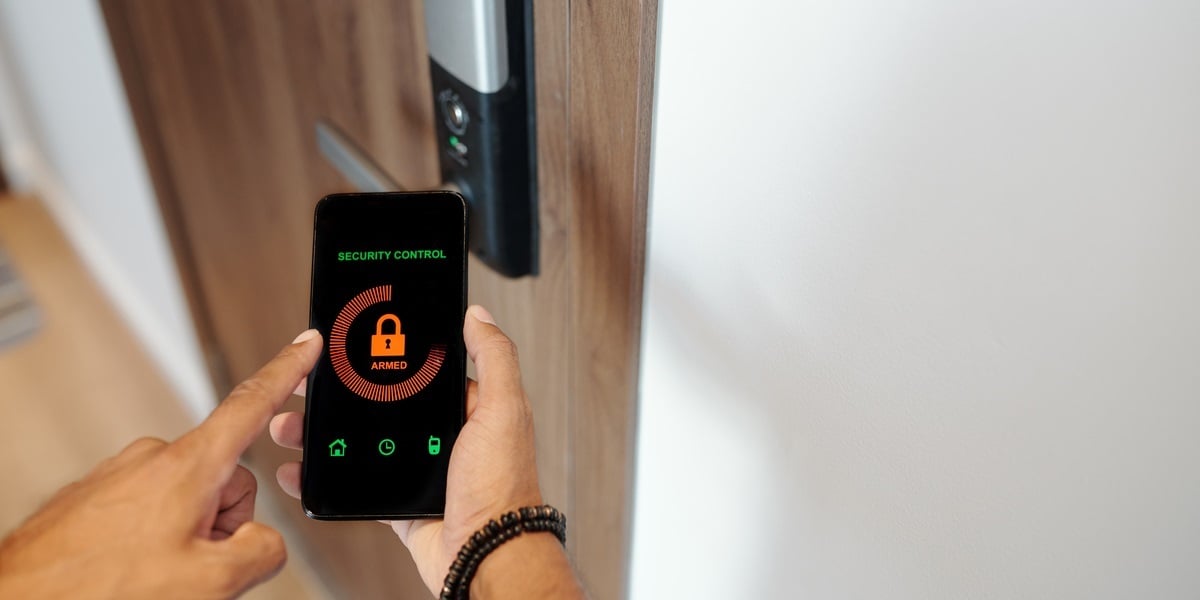 A woman unlocking her door with an app on her phone