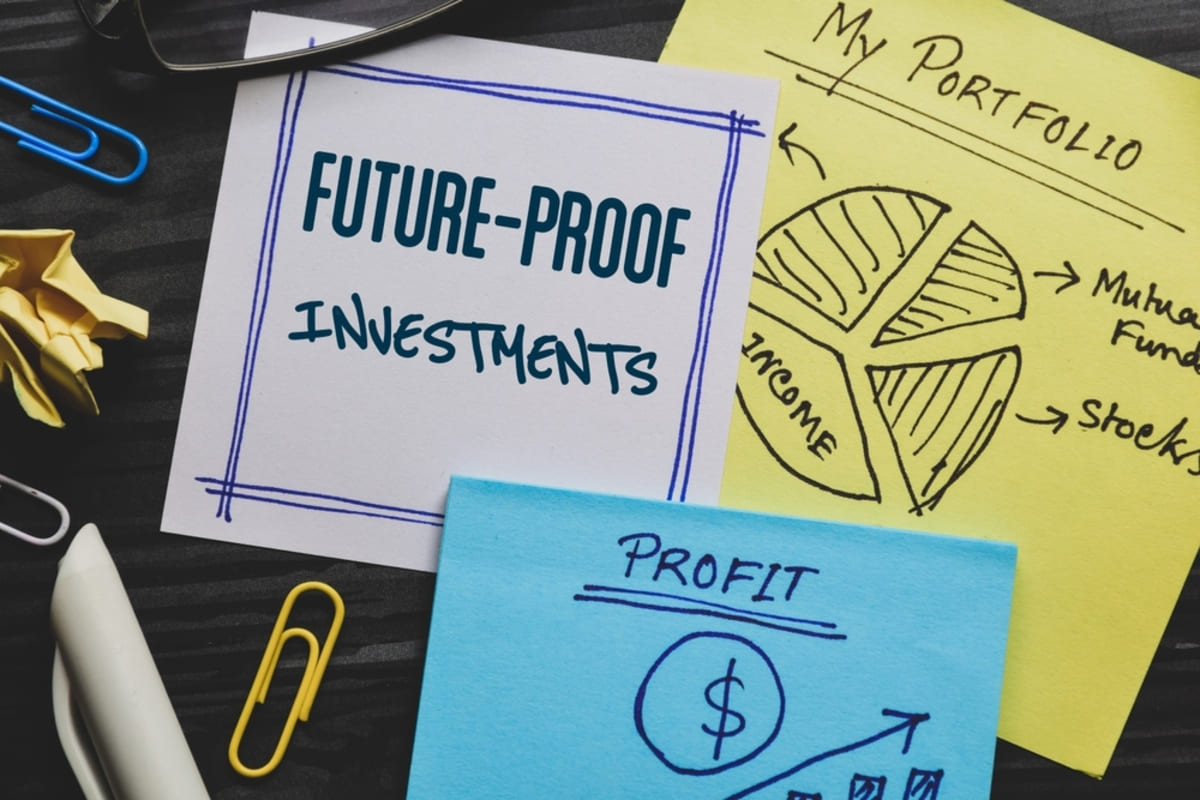 Future-proof investments inscription on piece of paper with hand-drawn personal portfolio and profit bar on desk. 