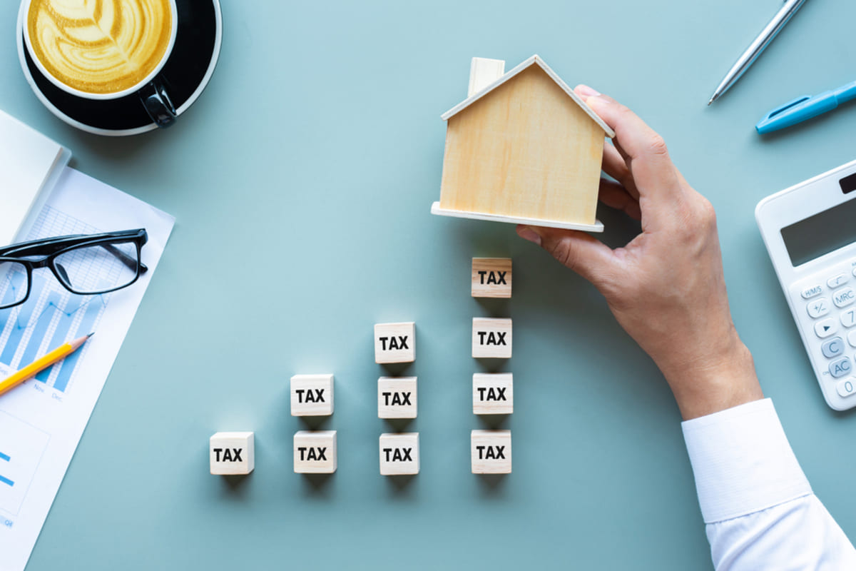 Wood model house with wooden cubes under that say tax.