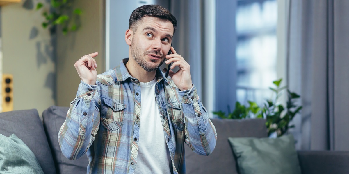 man at home on the couch, talking on the phone