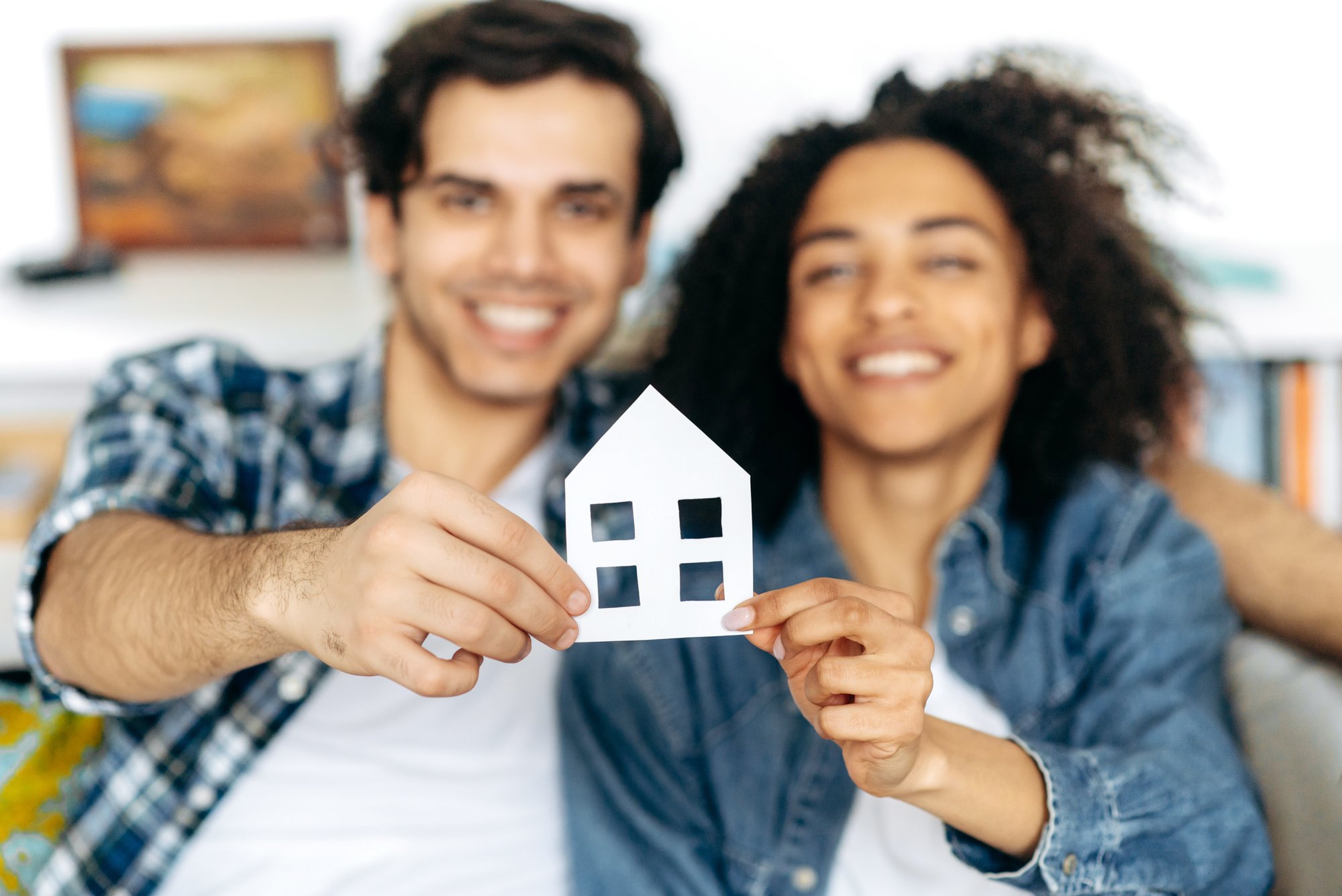 A happy couple holding up a house model cutout