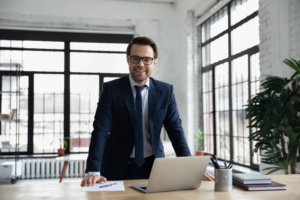 smiling confident young businessman in glasses posing in modern office