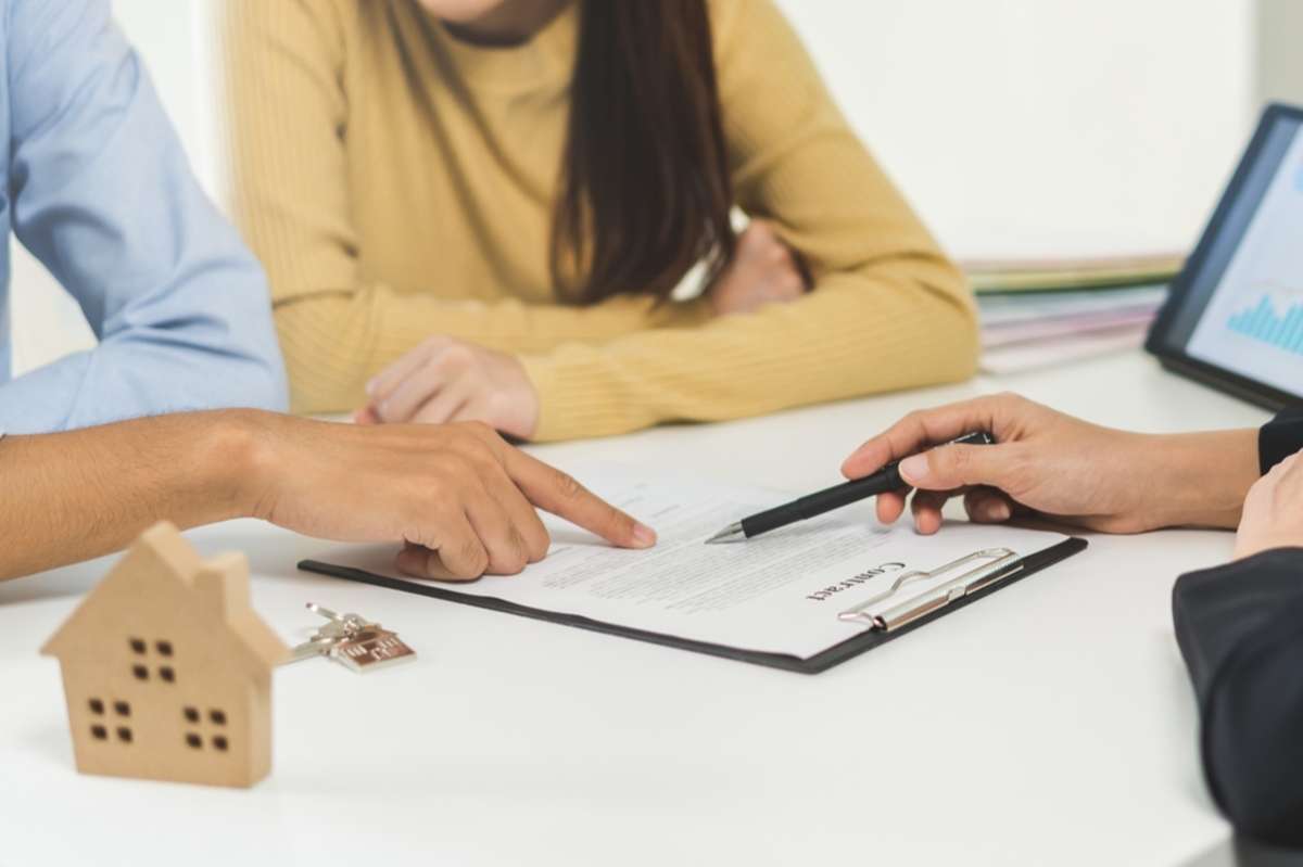 Hands point to document on the table with house model, lease renewal notice to tenant concept