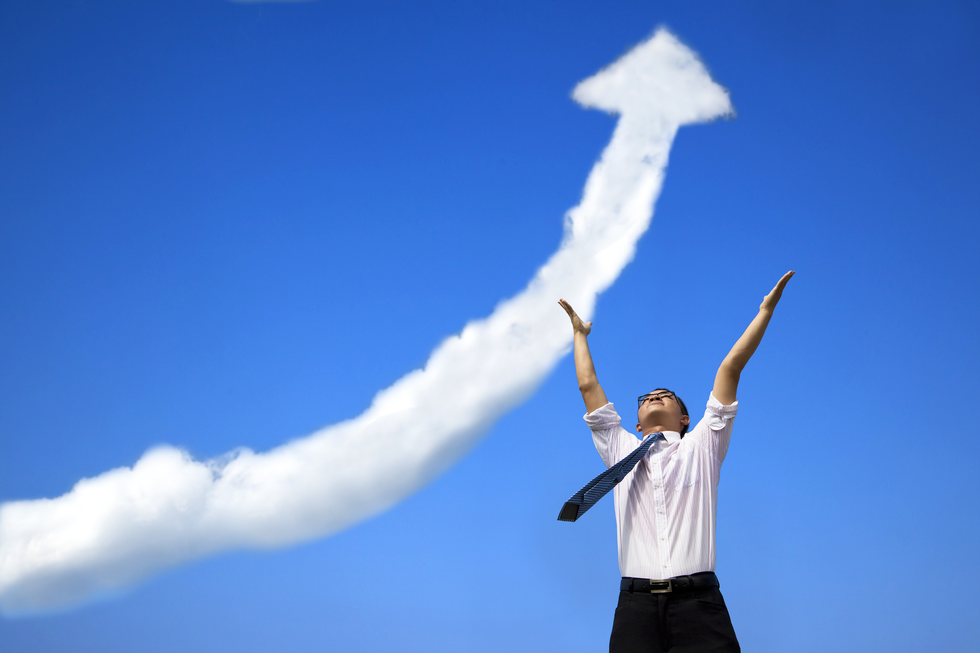 Businessman with raised hands looking up in the sky