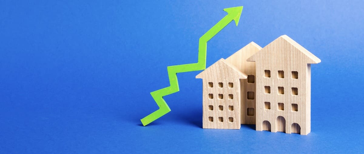 Wooden houses next to a green arrow going up on a blue background